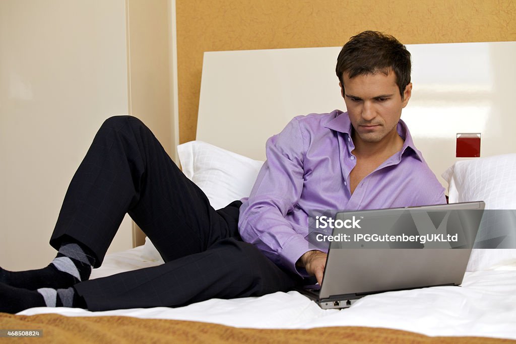 Young man using laptop on bed 20-29 Years Stock Photo