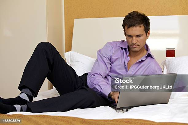 Young Man Using Laptop On Bed Stock Photo - Download Image Now - 20-29 Years, 2015, Adult