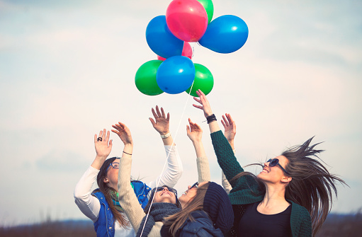 Group of female friends having fun with colorful balloons