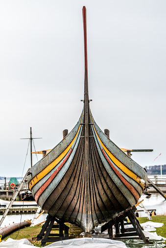 A closeup shot of an old broken boat on the coast against a blue sky.