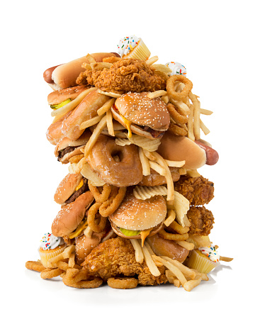 A large pile of junk food/fast food consisting of cheeseburgers, hamburgers, hot dogs, french fries, onion rings, cupcakes, potato chips, donuts and fried chicken.  The pile of junk food is isolated on a white background with clipping path.  Please see my portfolio for other food and drink images. 