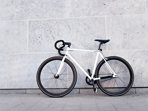 White bicycle leaning against light grey wall