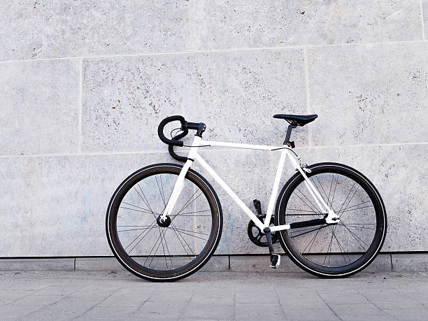 White bicycle leaning against light grey wall stock photo
