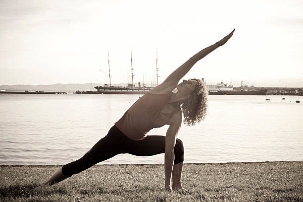 istock Woman in triangle yoga pose by the water 468526586