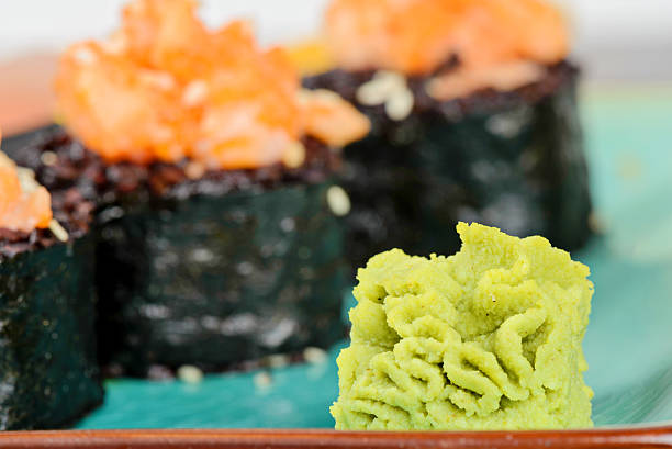 Wasabi with baked sushi rolls made from black rice and salmon, served on turquoise plate. Shallow depth of field. Focus on the wasabi.