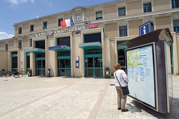 Train station of Angouleme, France Angouleme, France - June 26, 2013: Woman looking at timetables in front of train station. The station building is part of the former College Royal de la Marine angouleme stock pictures, royalty-free photos & images