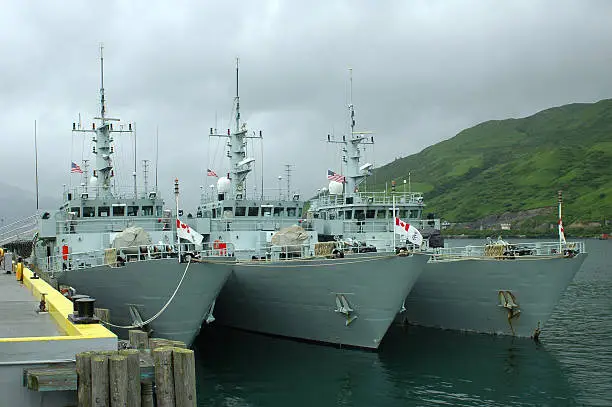 Three Canadian Navy mine-sweeping vessels are moored to a pier in Alaska