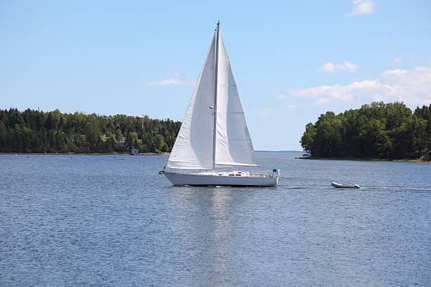 istock Sailboat sailing in the ocean towing a small boat. 468546492