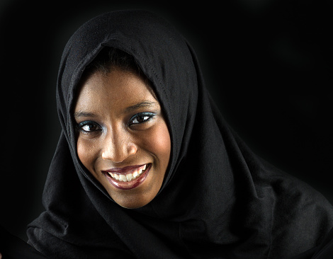 Smiling muslim teenage girl posing on black background  (this picture has been taken with a Hasselblad H3D II 31 megapixels camera)