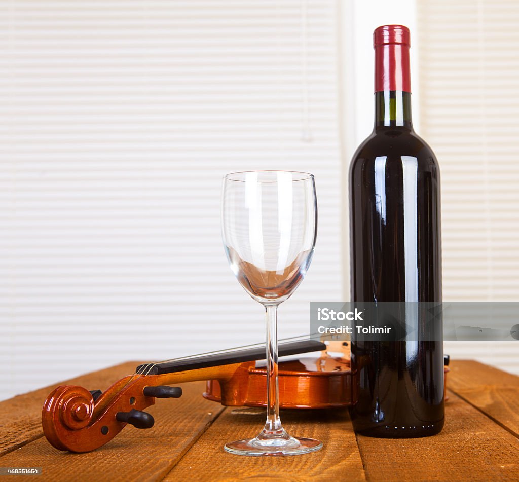 Music and wine glass and bottle of wine and old violin on wooden table 2015 Stock Photo