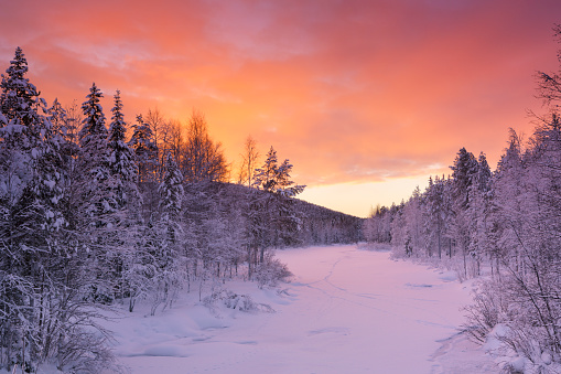 A frozen river in a wintry landscape. Photographed near Levi in Finnish Lapland at sunrise.