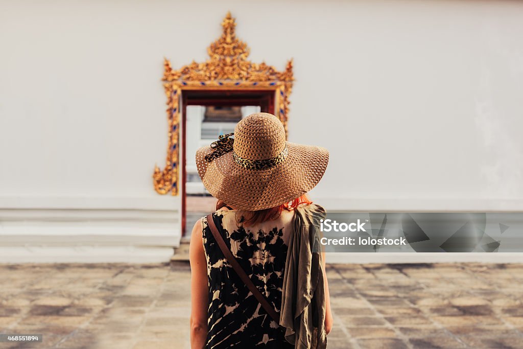 Woman looking at door to buddhist temple A young woman is looking at the elaborate entrance to a buddhist temple 2015 Stock Photo