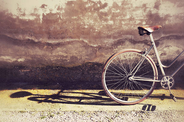 Close up detailed view of a vintage style white city bicycle with attached child seat parked beside an old rustic red brick wall in Bruges Belgium. The textured European architecture background historic bricks cobblestone pavement classic urban lifestyle and eco friendly bicycle commuting culture reflect everyday city life in Belgium