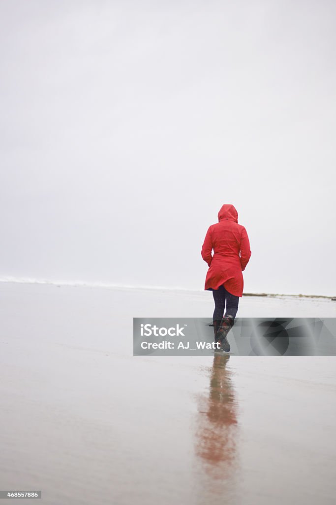 Seaside stroll on a rainy day Rearview shot of a young woman walking along the beach in rainy weatherhttp://195.154.178.81/DATA/i_collage/pu/shoots/785386.jpg Women Stock Photo