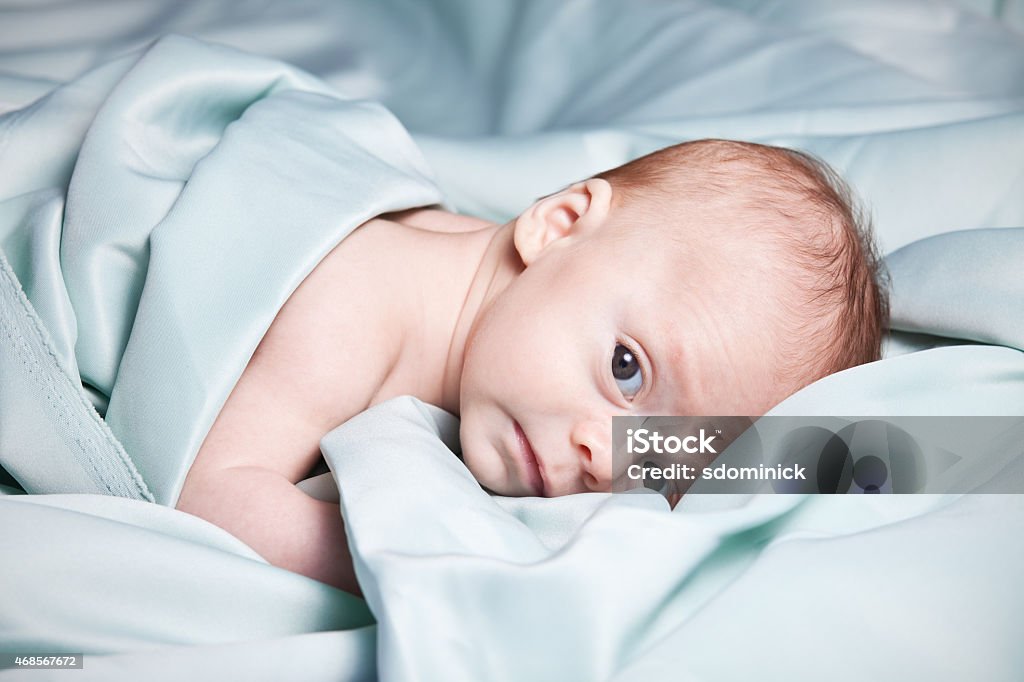 Adorable Baby Laying On Silky Blanket An adorable 2 month old baby laying down in a light green silky blanket. Blanket Stock Photo