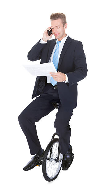 istock Businessman Riding Unicycle Talking On Cellphone 468571591