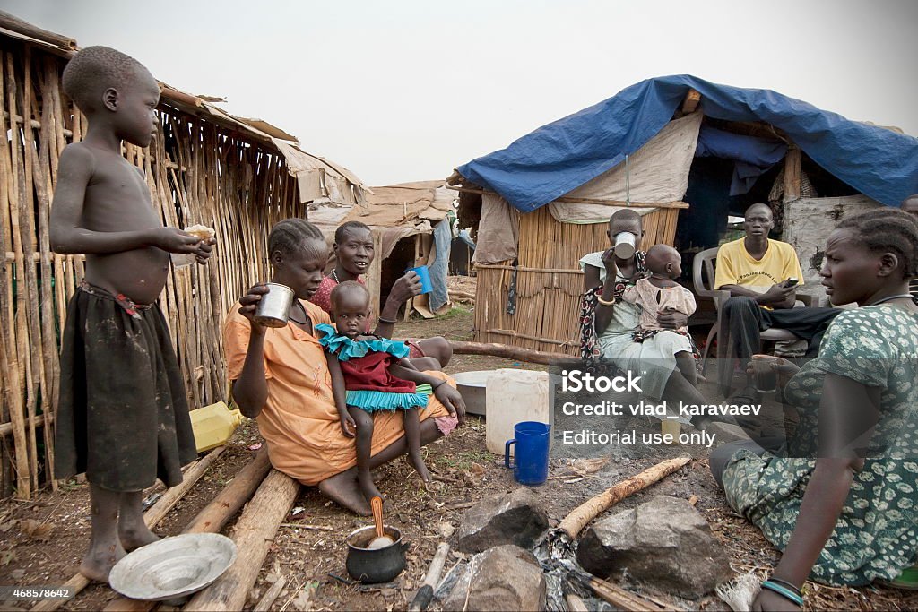 People have breakfast in displaced persons camp, Juba, South Sudan. Juba, South Sudan - February 28th, 2012: Unidentified people have breakfast in front of their huts in displaced persons camp, Juba, South Sudan, February 28, 2012. Refugee Stock Photo