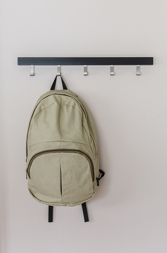 green backpack hanging on the wall