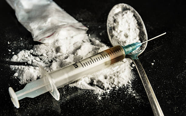 A drug syringe and a spoon with cooked heroin Drug syringe and cooked heroin on spoon narcotic stock pictures, royalty-free photos & images