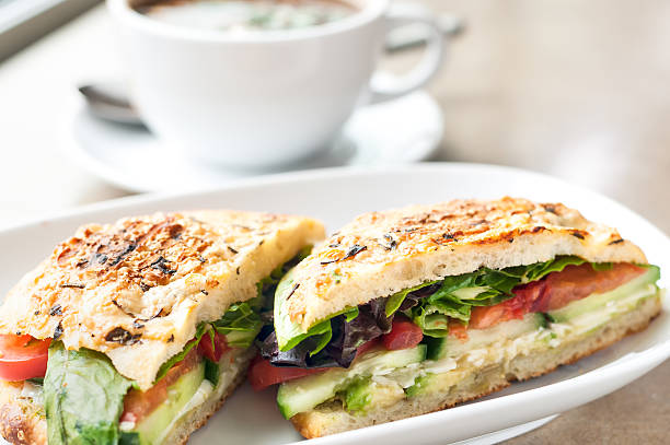 Vegetarian Focaccia Bread Sandwich and Soup Rosemary focaccia bread sandwich of avocado, cucumber, tomatoes & lettuce and black bean soup in the background of a restaurant. cafe sandwich stock pictures, royalty-free photos & images
