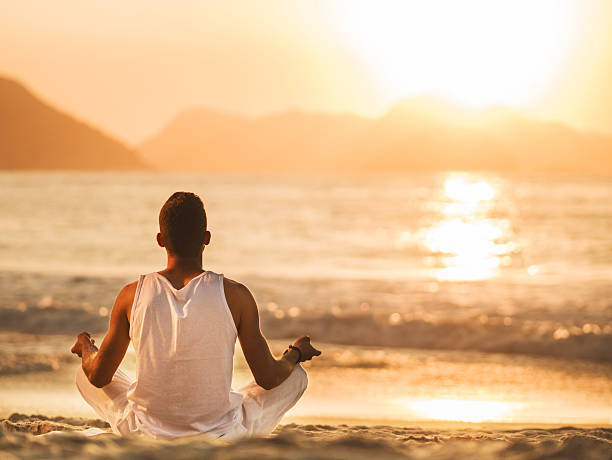 istock Rear view of a man meditating on beach at sunset. 468585616