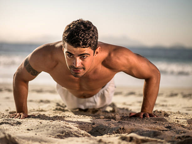 istock Latin American man doing push-ups on the beach. 468590186
