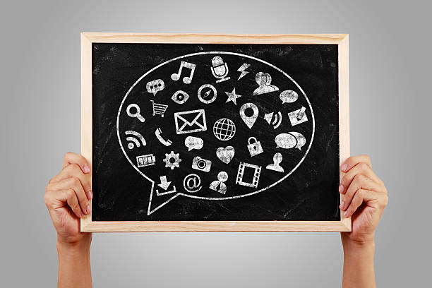 Social media concept blackboard is holden with hands against gray background.