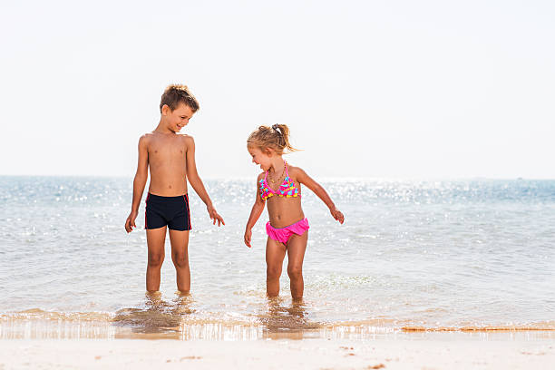Playful siblings having fun at sea during summer day.