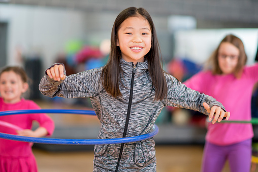 A multi ethnic group of elementary age girls hula hooping at recess or daycare.