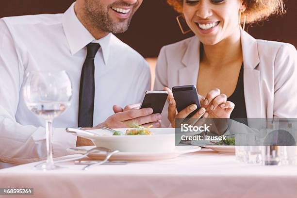 Businessman And Businesswoman Using Smart Phones At Lunch Stock Photo - Download Image Now