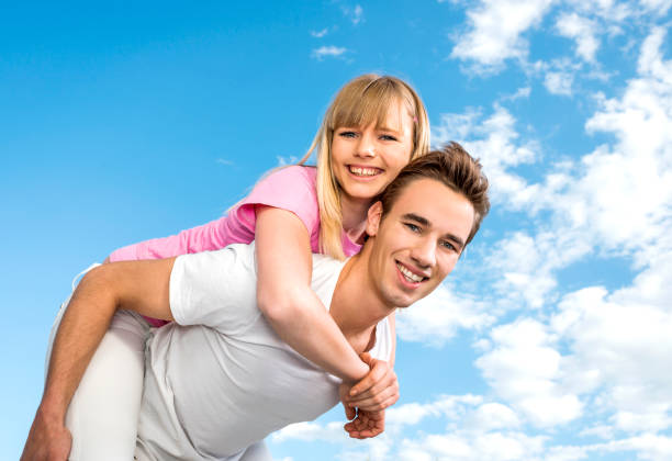 istock Smiling couple piggybacking against the sky. 468598414