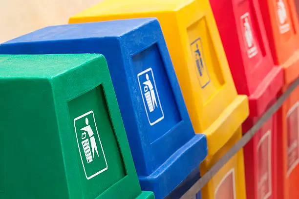 A row of recycling bins in different colors at a recycling station.