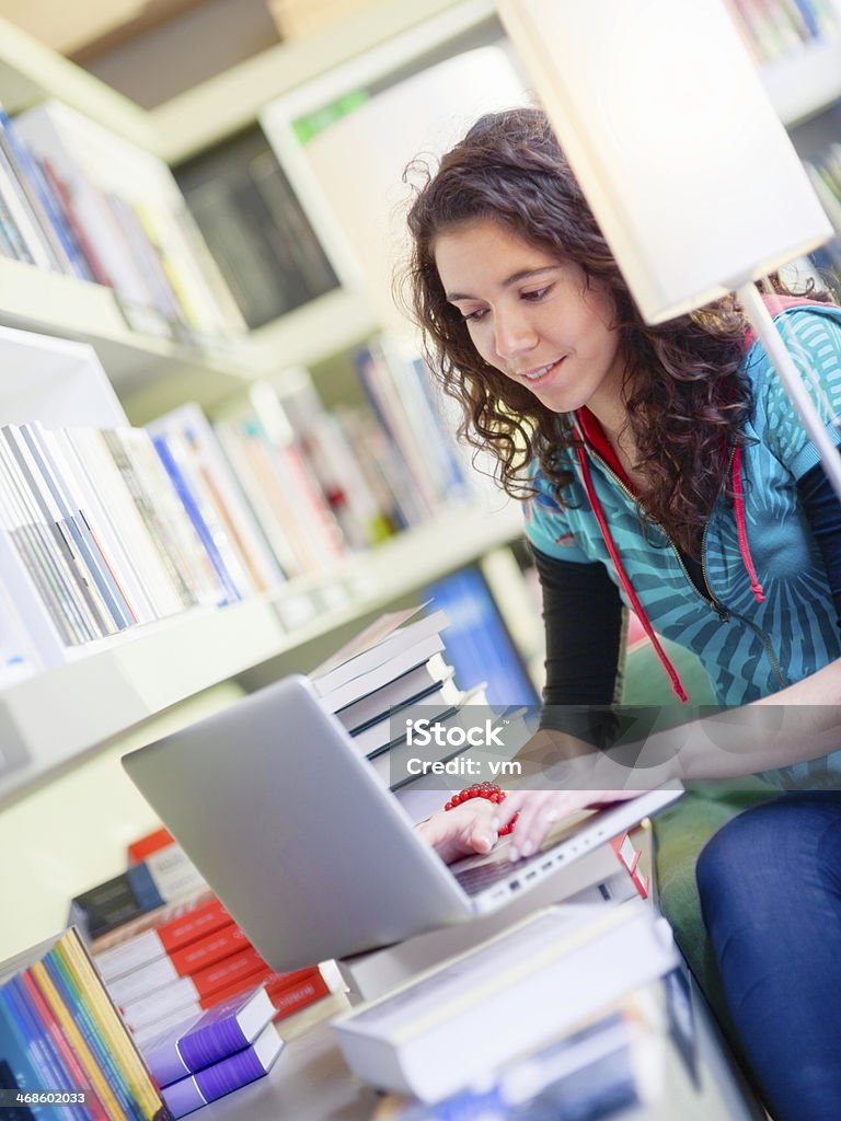 Mujer joven con ordenador portátil en la biblioteca - Foto de stock de 20-24 años libre de derechos