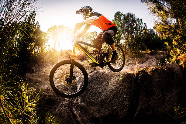 Extreme mountain biker riding over rough terrain Extreme trail rider maneuvering his mountain bike over rough terrain on an off-road trail mountain bike stock pictures, royalty-free photos & images