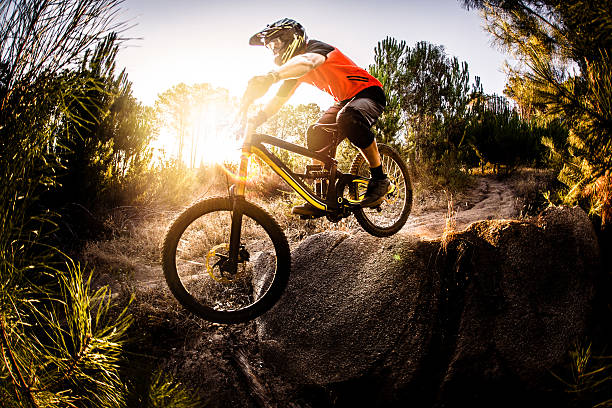 Extreme mountain biker riding over rough terrain Extreme trail rider maneuvering his mountain bike over rough terrain on an off-road trail bicycle stunts stock pictures, royalty-free photos & images