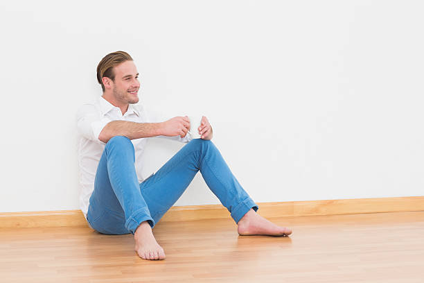 istock Casual man sitting on floor holding cup 468607584