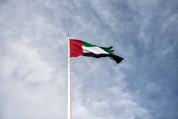 United Arab Emirates flag against a cloudy blue sky stock photo