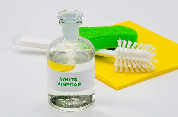 White vinegar in a glass bottle. White background. Organic cleaner.