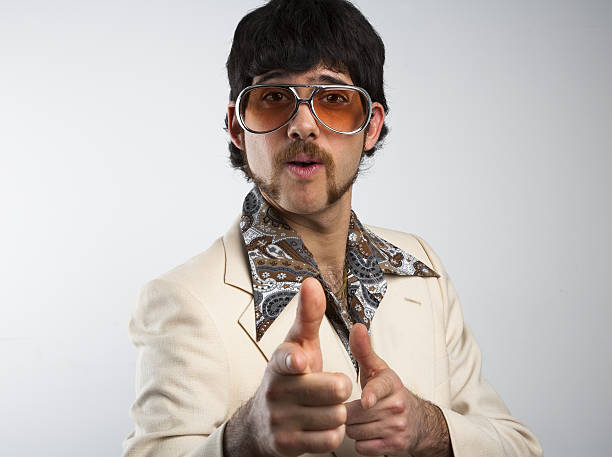 A man dressed in clothes from the '70s on a white background Portrait of a retro man in a 1970s leisure suit and sunglasses pointing to the camera vintage fashion stock pictures, royalty-free photos & images
