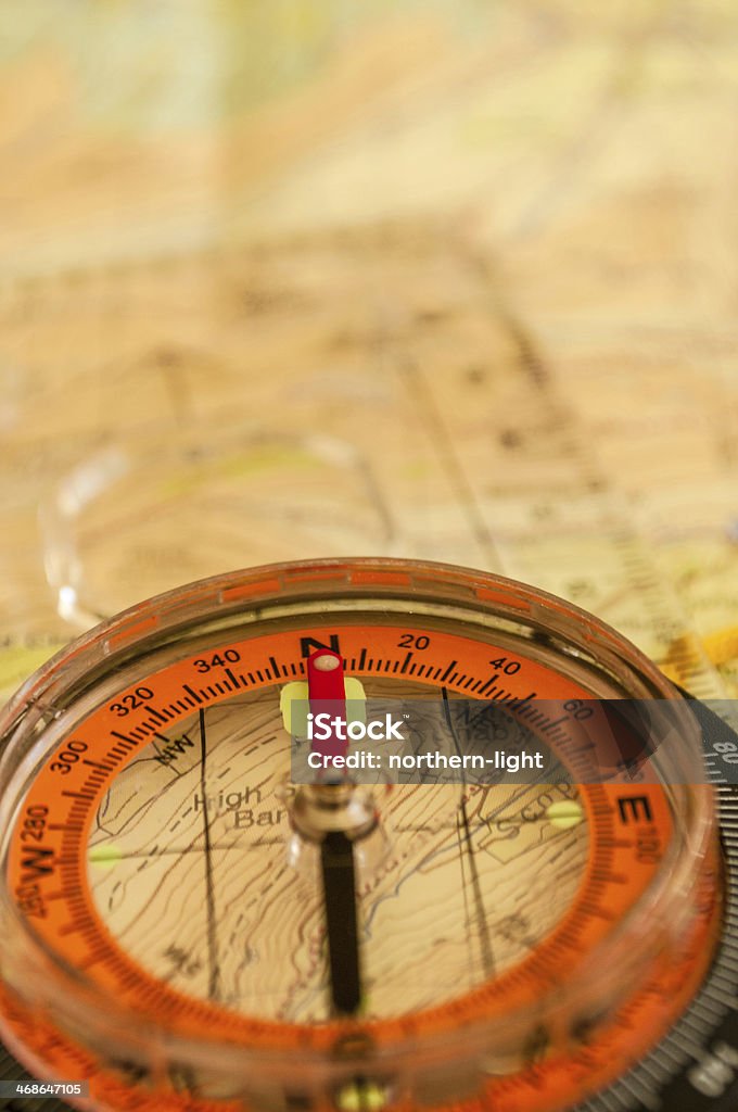 Close-up of a compass on a topographic map Compass showing direction on Topographic Map,Shallow Depth of Field Adventure Stock Photo