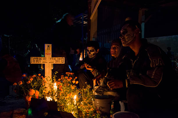 Day of the Dead at cemetery in Xoxocotlán, Oaxaca, Mexico Oaxaca, Mexico - October 31, 2014: During Day of the Dead celebrations ("Día de los Muertos" in Spanish), young men sit beside a loved one's grave at the cemetery in Xoxocotlán, on the outskirts of Oaxaca, Mexico. day of the dead photos stock pictures, royalty-free photos & images