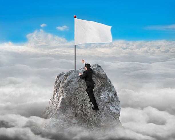 istock Businessman hand wanting for white flag on peak with cloudscape 468647412