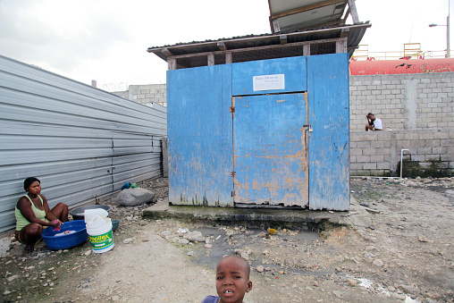 Port-au-Prince, Haiti - January 12, 2015: A woman washes clothes next to an abandoned structure provided by an international NGO (Non-Governmental Organization) after the January 12, 2010 earthquake in Camp Chavez in the Carrefour neighborhood.  The original residents of Camp Chavez lived for over a year after the earthquake on a highway median on the Route des Rails in Carrefour.  The residents re-named the neighborhood for Venezuelan president Hugo Chavez after his death.