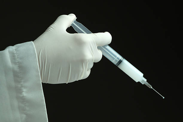 istock hand with protective glove injecting drug with syringe. 468657476