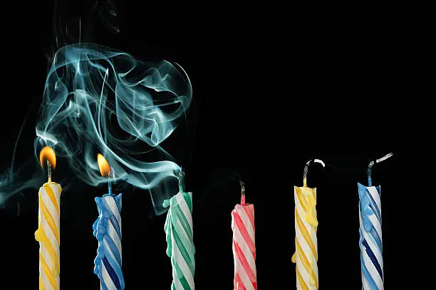birthday candles that have just been blown out with smoke on black background