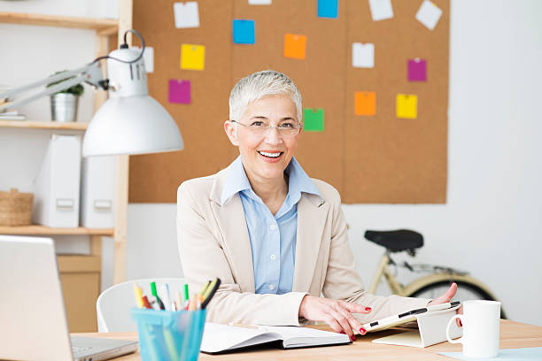 istock Beautiful cheerful mature woman at office working on computer 468663022