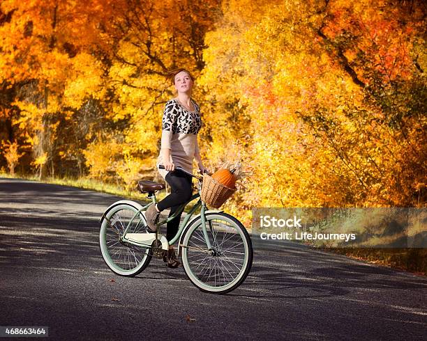 Young Woman Riding Her Bike On A Paved Autumn Pathway Stock Photo - Download Image Now