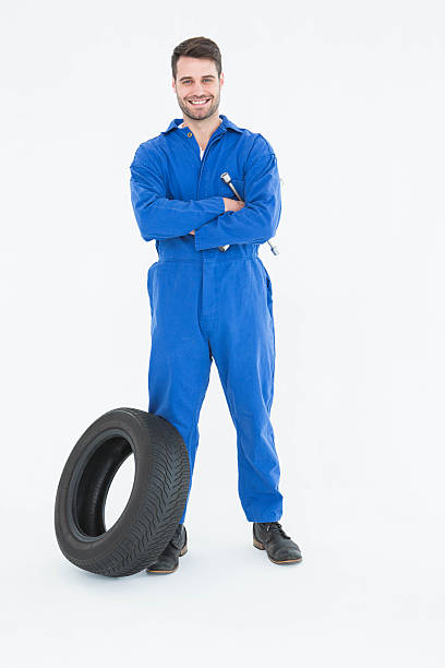istock smiling mechanic with arms crossed standing by tire 468670914