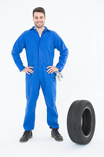 istock Smiling mechanic with hands on hips standing by tire 468670916