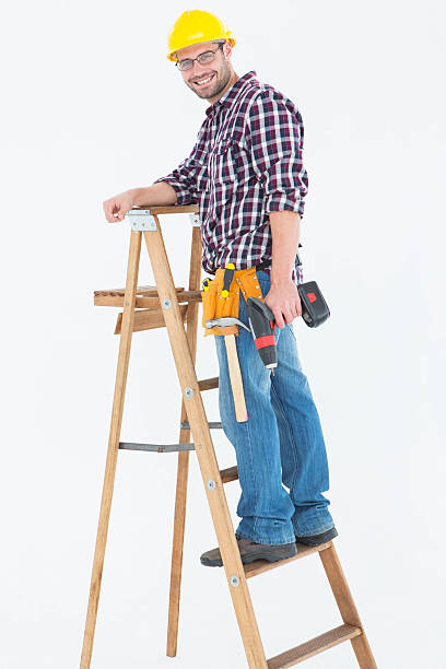istock Repairman climbing ladder while holding power drill 468674102